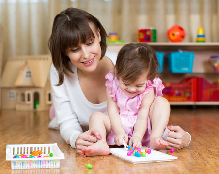 mom and her kid girl play toys in children room