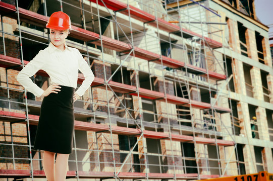 Female engineer woman in red safety helmet on construction site