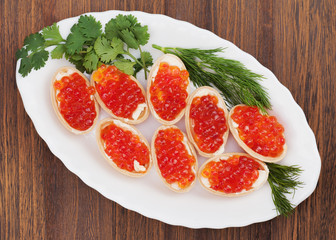 Tartlets with red caviar on wooden background.