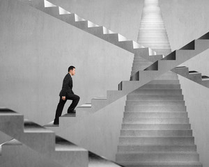 Businessman climbing on concrete stair maze
