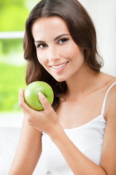Young happy smiling woman with apple, at bedroom