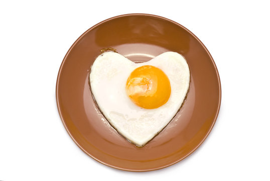 Heart-Shaped Fried Egg on Brown Plate isolated on white