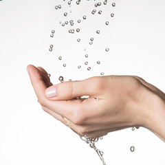 female hands under the falling drops of  water