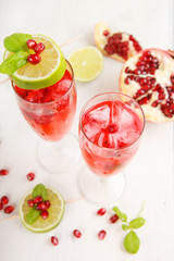 Two glasses with red pomgranate champagne, lime and mint.