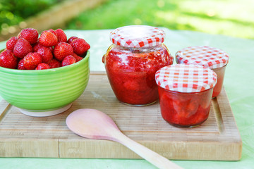 Homemade strawberry jam in different jars and fresh ripe strawbe