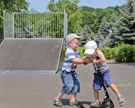 Two young boys fighting over a scooter