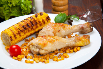 chicken thigh with a boundary of corn cob and salad
