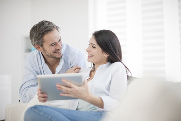 Obraz na płótnie Canvas Cheerful couple using digital tablet at home