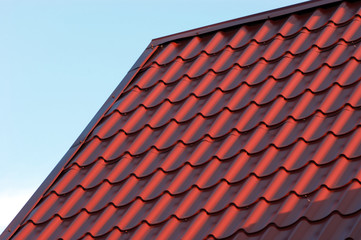 Part of red house roof from metal tile over blue closeup