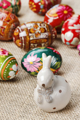 Obraz na płótnie Canvas Easter eggs and ceramic rabbit on jute background