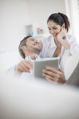 Cheerful couple using digital tablet at home