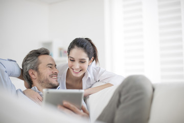 Cheerful couple using digital tablet at home