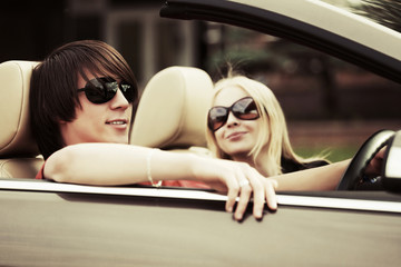 Happy young couple driving a convertible car