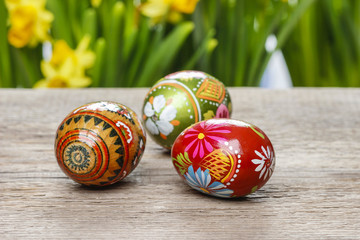Easter eggs on wooden table. Yellow daffodils in the background