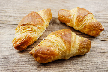 French croissants made of puff pastry on wooden table.