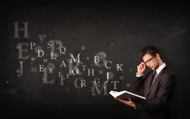 Young man reading a book with alphabet letters