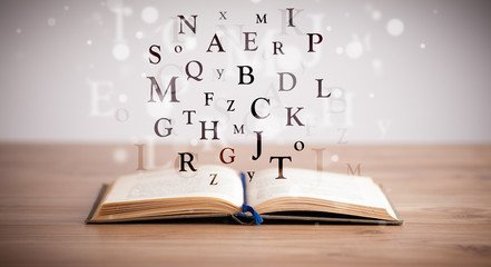 Opened book with flying letters
