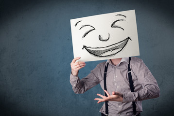 Businessman holding a paper with smiley face in front of his hea