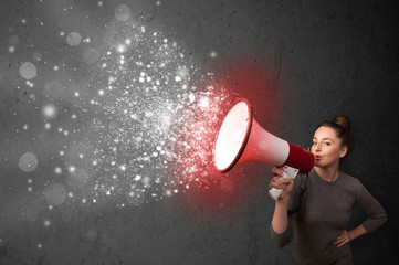 Woman shouting into megaphone and glowing energy particles explo
