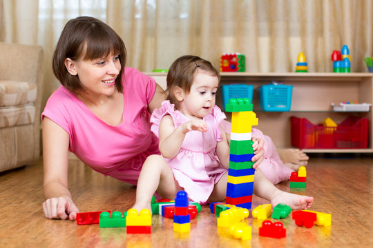 mother and her daughter play with toys at home interior