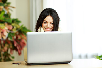 Young cheerful woman working on a laptop at home