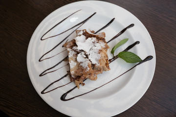 Top view of piece of apple strudel with mint and chocolate