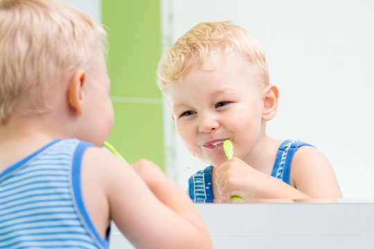 child boy brushing teeth in bathroom