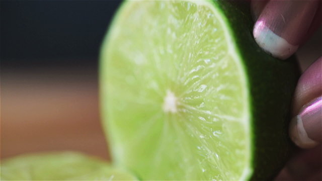 Woman hands cut lime into slices, closup