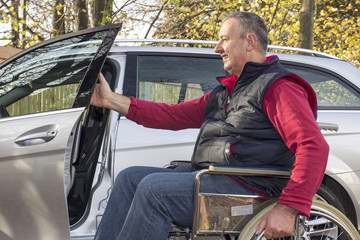 Man in a wheelchair in the fall next to their car