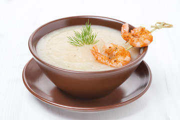 Potato cream soup with glazed shrimp on a skewer, close-up