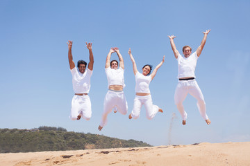 group of friends jumping on beach