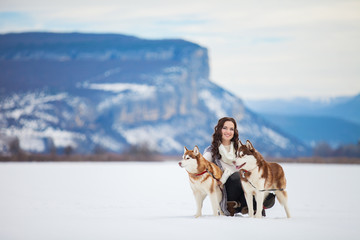 young girl playing with siberian husky dogs in winter park