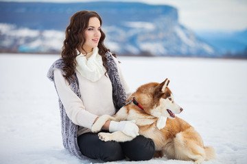 young girl playing with siberian husky dogs in winter park