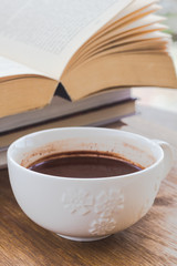 Cup of chocolate on a wooden surface with books