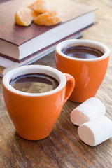 Two cups of chocolate with marshmallows on a wooden table