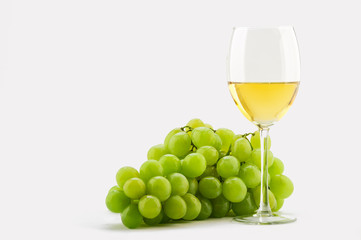 glass of white wine and green grapes on a white background