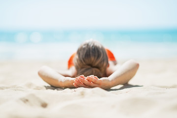 Fototapeta na wymiar Young woman laying on beach. rear view