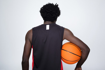 Back view of a basketball player holding a ball against gray bac