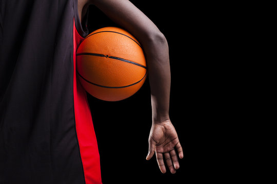 Image of a basketball player holding a ball against dark backgro