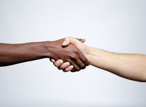 Handshake between african and a caucasian man over gray backgrou