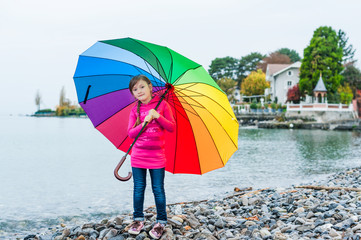 Portrait of a cute little girl with big colorful umbrella