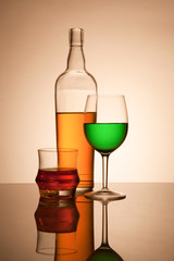 Still life composition with glasses and bottle filled with color