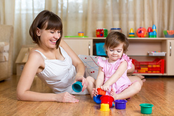 Obraz na płótnie Canvas kid and mother play together with cup toys