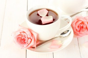 cup of tea with roses on white wooden table
