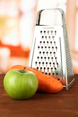 Metal grater and apple, carrot, on bright background