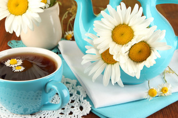 Fototapeta na wymiar Beautiful bouquet chamomiles in teapot on wooden table close-up