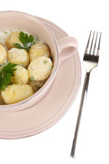 Tender young potatoes with sour cream and herbs in pan isolated