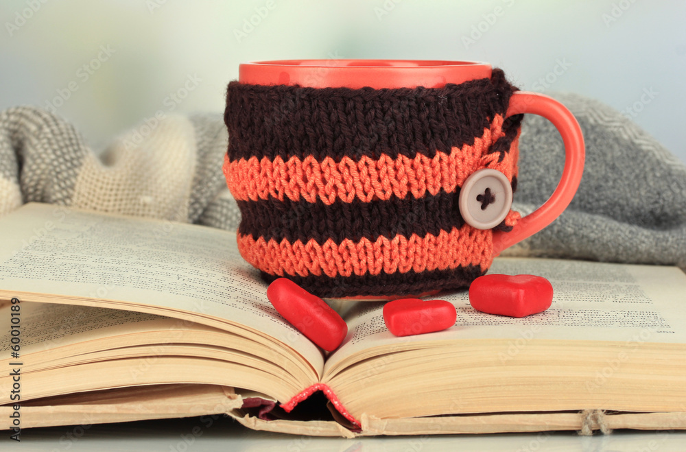 Aufkleber cup with knitted thing on it and open book close up