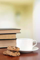 Cup of coffee with cookies and books