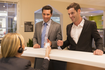 Businessmen communicating with female receptionist